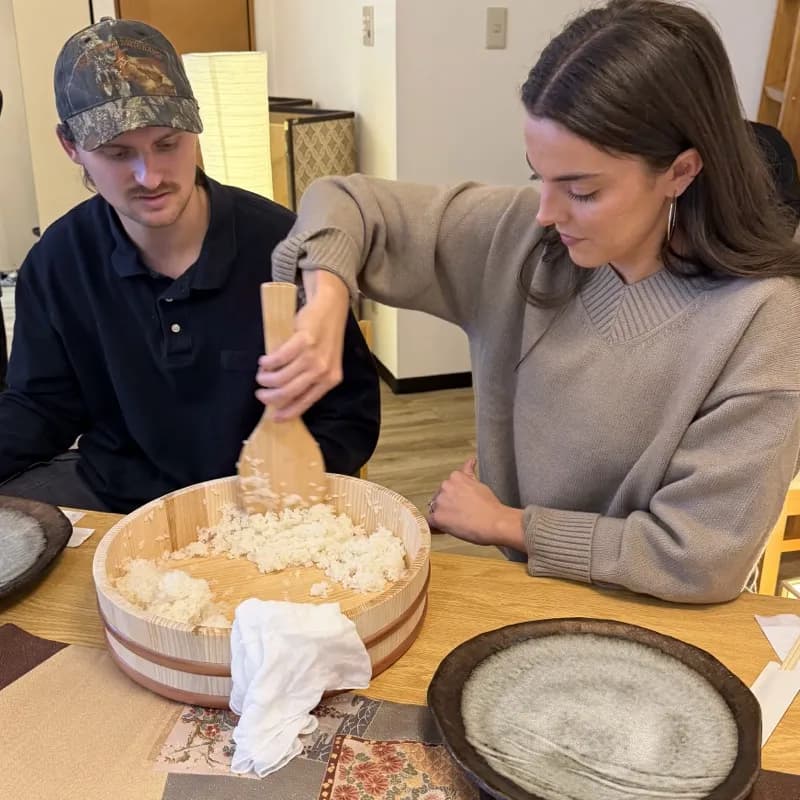 Guests mixing sushi rice in traditional wooden hangiri